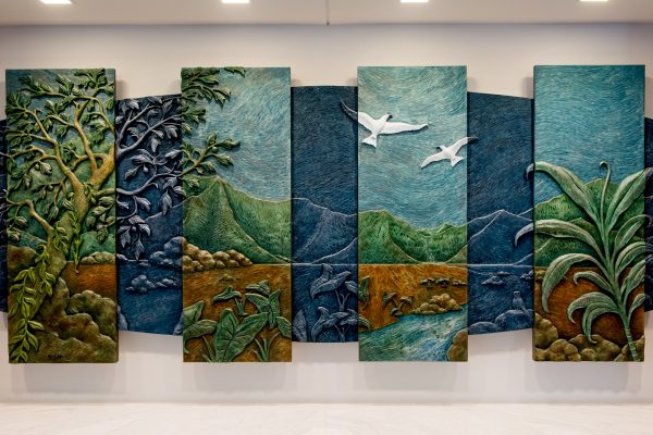 5’ x 10.5’ x 2.5” acrylic on hand carved Precision Board
In this Hawaiian mountain valley landscape, the scene is broken up into two levels symbolizing Day and Night, the Present and the Past. The panels of the day are vertical and geometric, lit by daylight, standing like skyscrapers in a modern city skyline. The panels of the night recede to the back, illuminated by the silver blue light of the full moon and shaped like an Ark carrying the present on its way to the future. Amidst the landscape are four native plants, Kalo, Ti, Kukui and Maile, that represent in ancient Hawaiian times essential qualities of Justice. There are also two animal spirits or aumakua, the Owl, always watchful, and the mated pair of Fairy Terns, sentinels of the City of Honolulu.
Created for the law offices of Goodsill, Anderson, Quinn & Stifel in downtown Honolulu, Hawai’i .
Completed February 2013